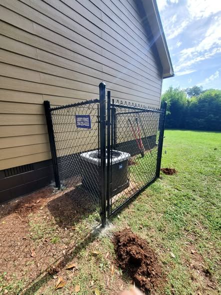 Black chain link security enclosure protecting an AC unit