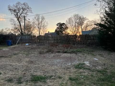 Before: failing fence line overgrown at dusk