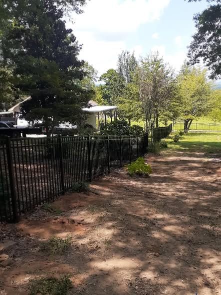 Black aluminum fence along a gravel farm drive