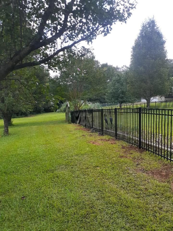 Black aluminum flush top fence descending a hillside
