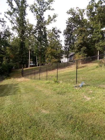 Black vinyl coated chain link fence running down a slope