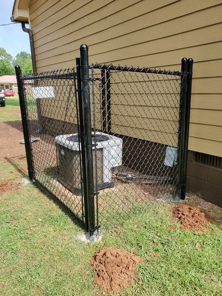 Black chain link cage guarding an AC unit against copper theft