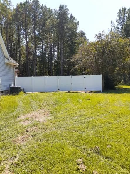 White vinyl privacy fence with a level top line on a wooded lot