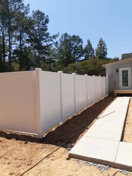 New white vinyl privacy fence beside a concrete walkway