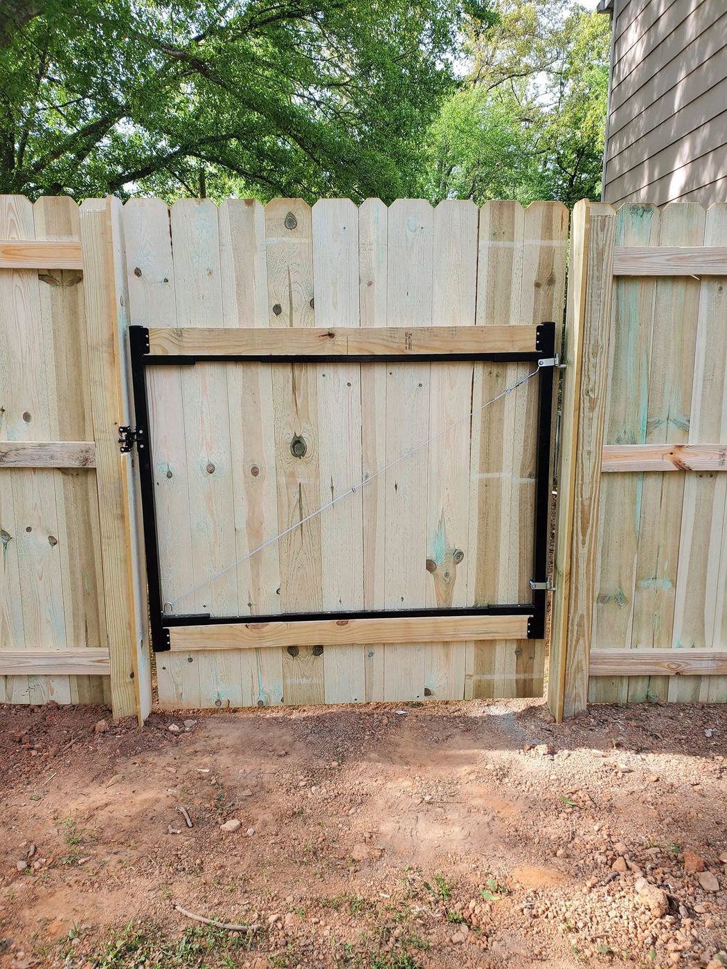 Steel gate frame detail with cable brace on a wood gate