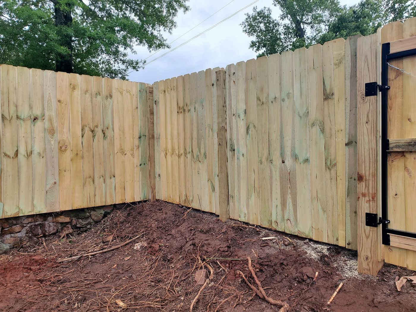 Wood privacy fence corner with walk gate near a black steel frame