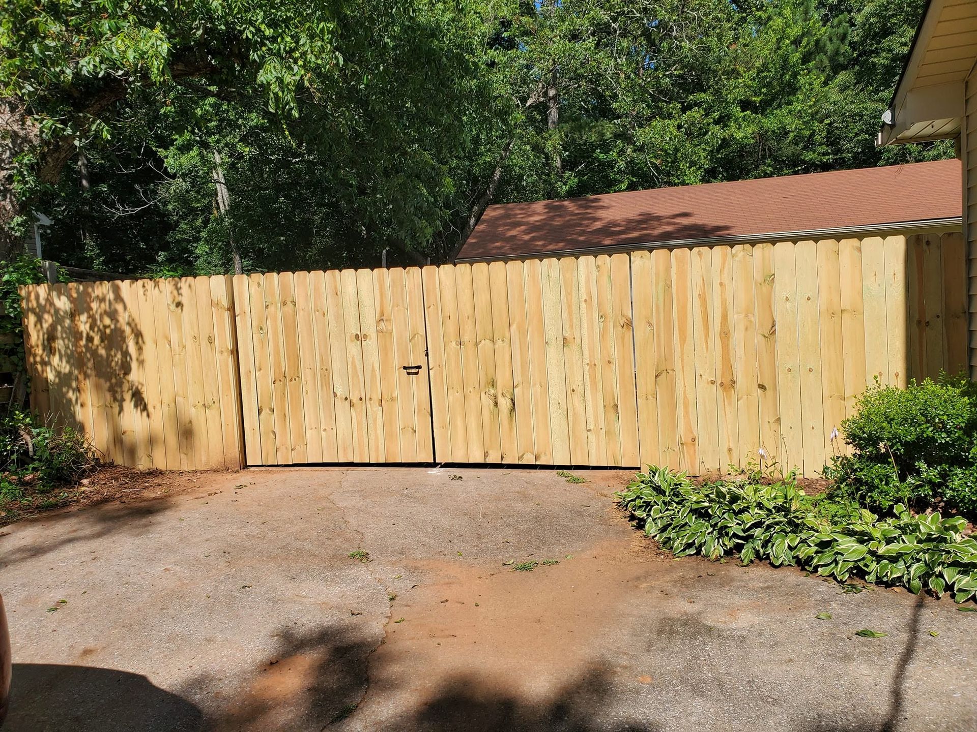 Wood privacy fence and double drive gates built by Liberty Fence across a shaded Oxford driveway