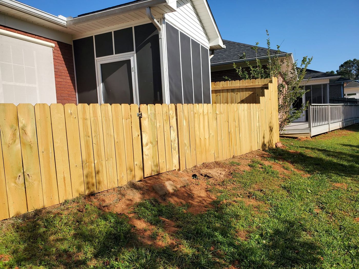 Wood privacy fence following the yard beside a screened porch