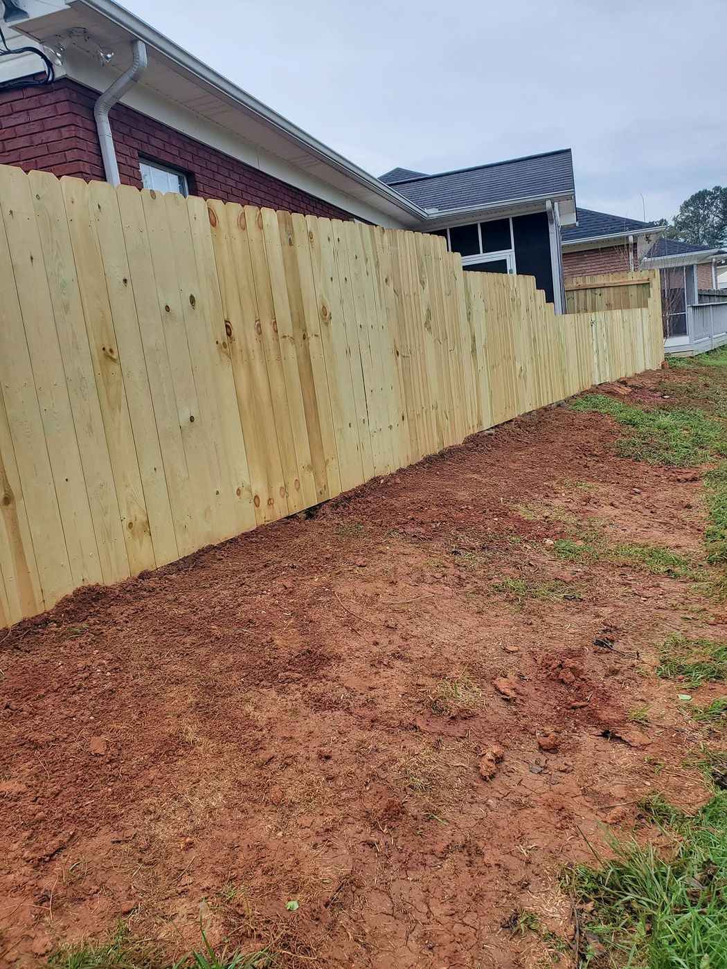 Wood privacy fence stepped beside a brick home